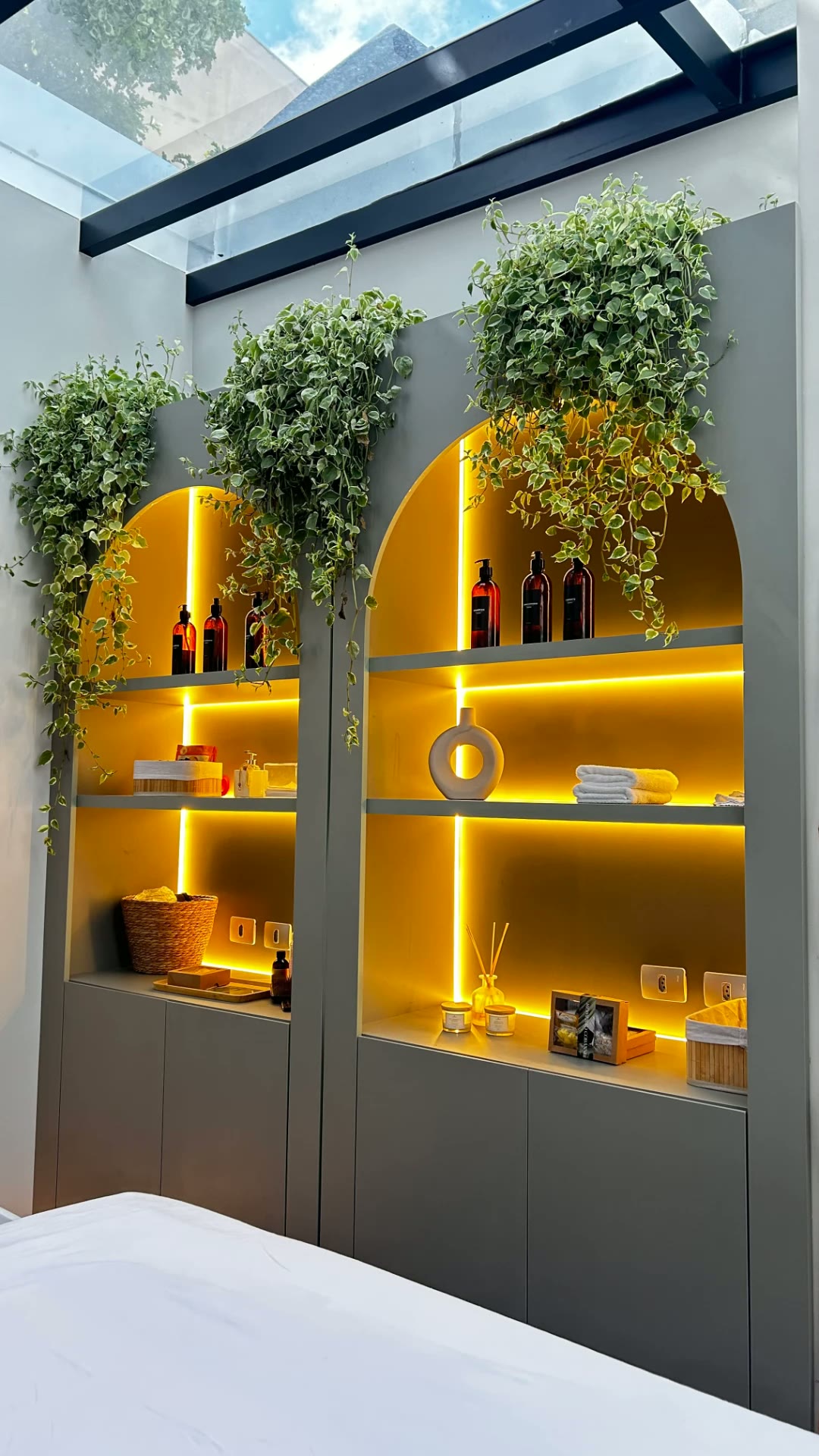 Detalhes do espaço: nichos iluminados e plantas sob o teto de vidro